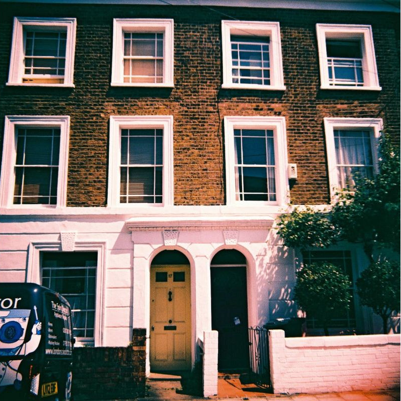 Traditional brick house with white-framed windows and a van parked outside.