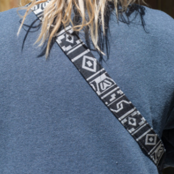 A camera strap with a multicolored pattern and black leather ends.