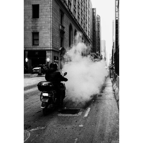 Person on a motorcycle with smoke in an urban setting