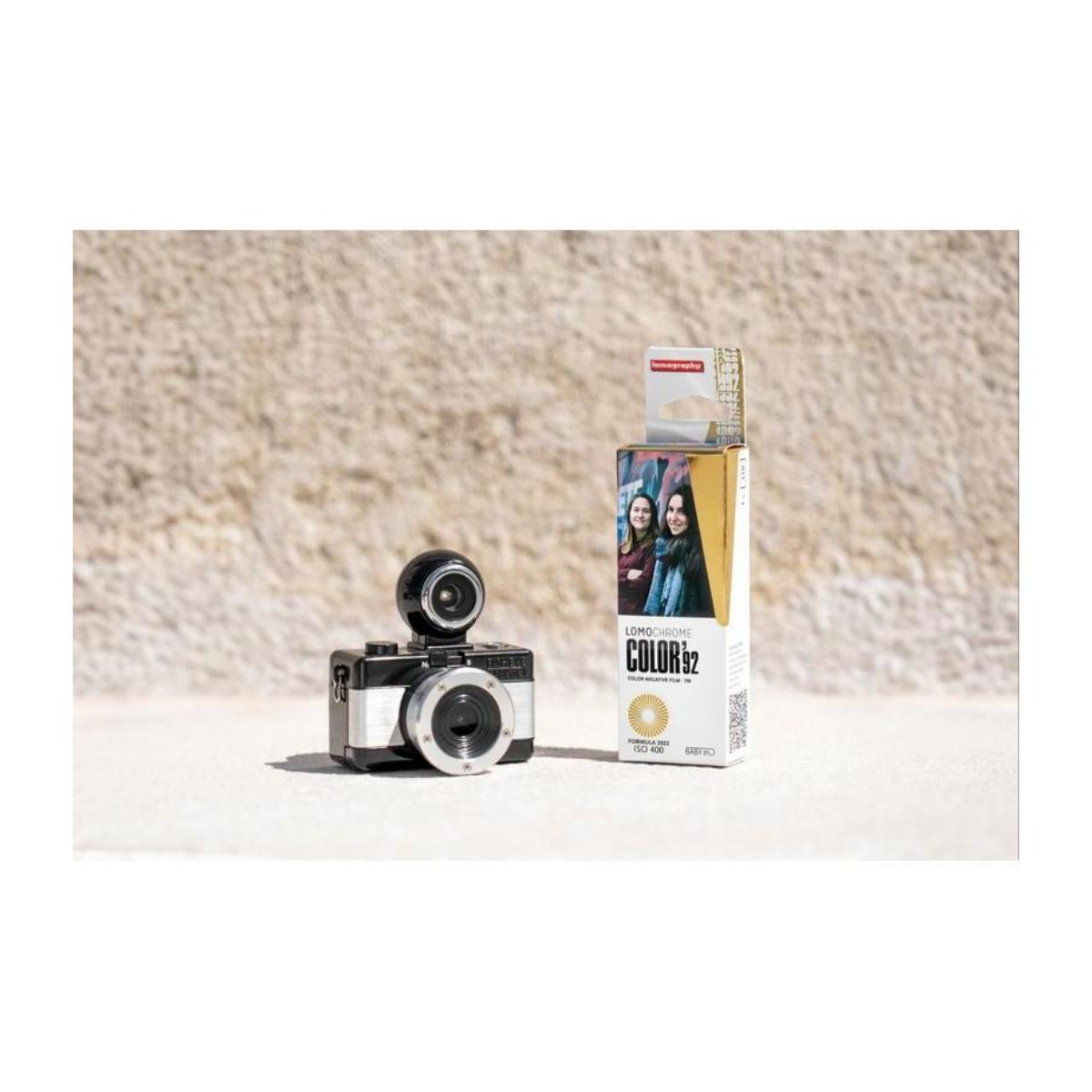 LomoChrome Color '92 110 film box next to a compact 110 film camera on a textured stone surface.