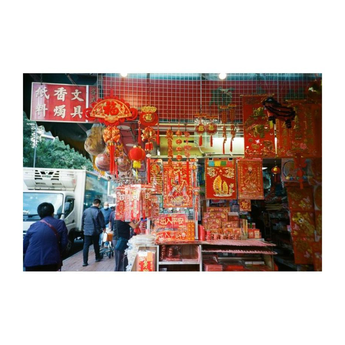 Street market stall decorated with vibrant red Chinese New Year ornaments, lanterns, and traditional paper decorations.