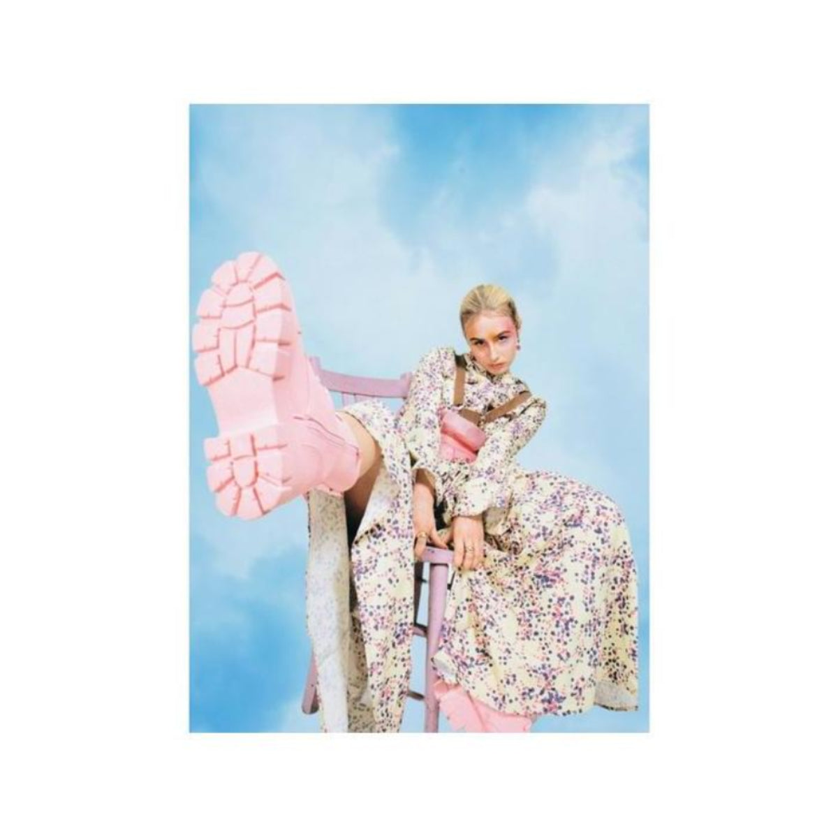 Person in a floral dress and chunky pink boots sitting on a chair against a blue sky, captured on Lomography 400 film.