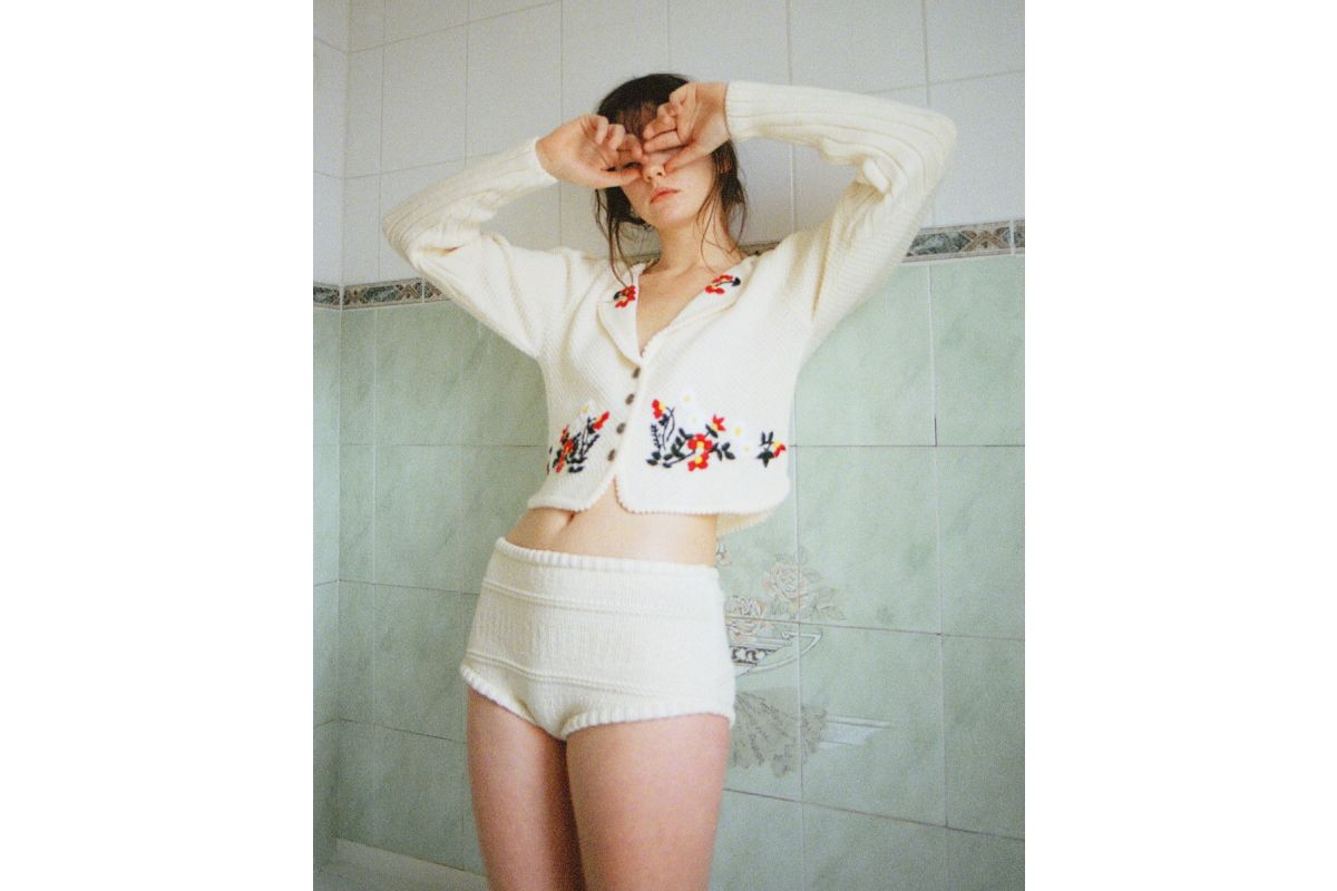 A person wearing a white floral cardigan and knit shorts, captured with the bold, grainy aesthetic of Lomography 800 film.