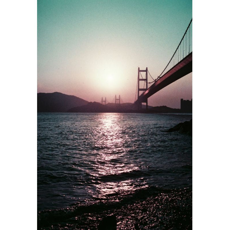 Golden Gate Bridge at sunset with vintage purple and teal color shifts captured on 35mm film.