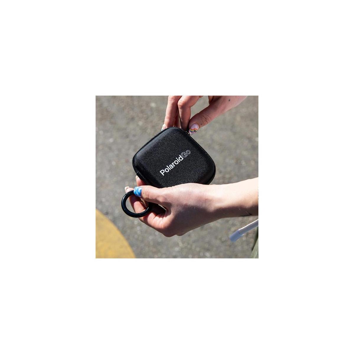 Compact black Polaroid Go pocket photo album with a textured finish and a convenient carrying ring held in hands.