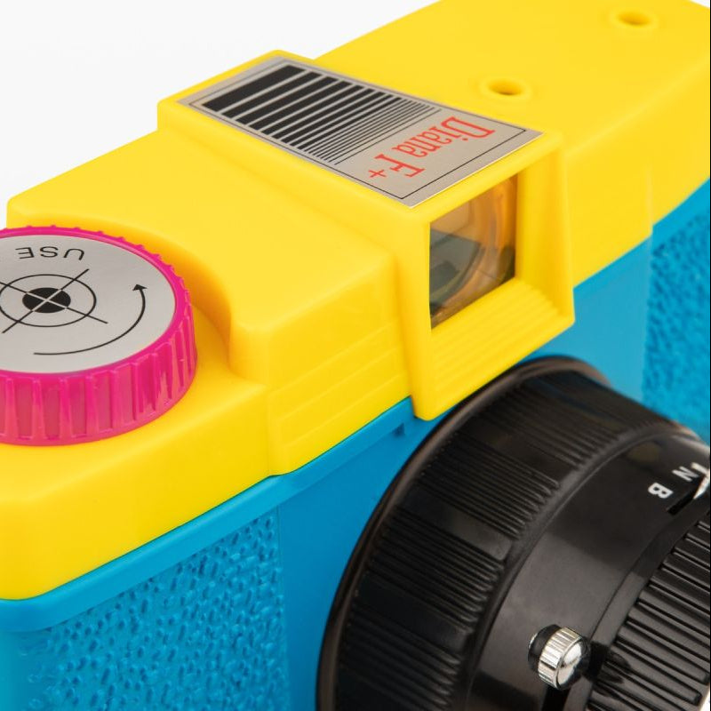 Close-up of a yellow and blue toy camera with lens cap on a black background