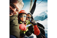 Two people in a helicopter with snowy mountains in the background