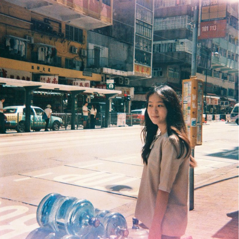 Woman standing on a city street with water bottles on the ground
