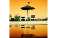 Poolside setting with a thatched umbrella and chairs on a yellow-orange gradient background