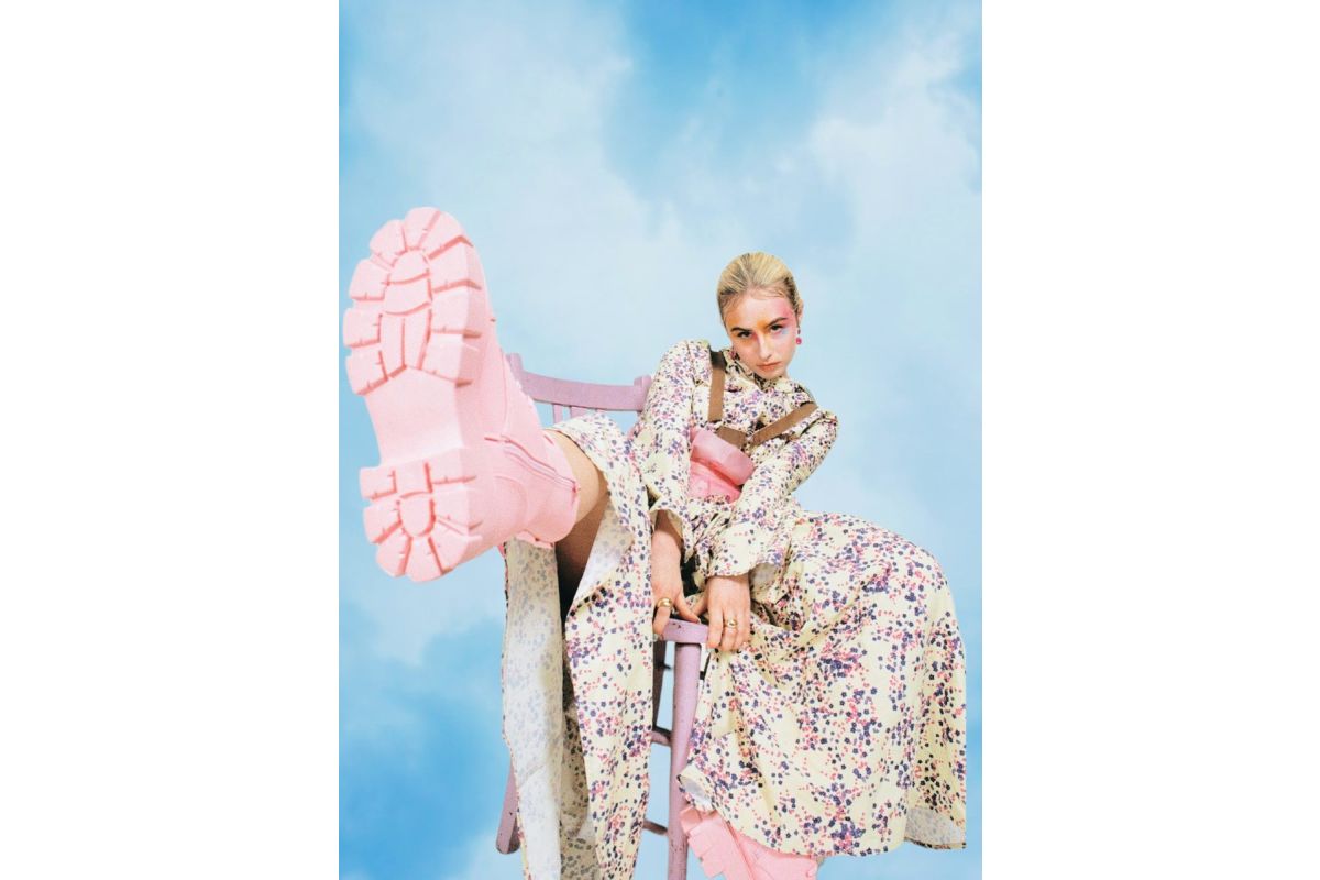 Person sitting on a chair with pink shoes in front of a blue sky