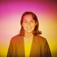 Person wearing a dark blazer against a colorful gradient background