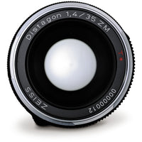 A close-up studio shot of a Zeiss Distagon 1.4/35 ZM lens, showing the front glass element, black and silver metal barrel, and white engraved text on a clean white background.