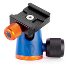 A blue and black camera tripod ball head with bright orange adjustment knobs and a black quick-release plate, shown on a clean white background.