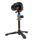 A black camera with a lens attached, mounted on a three-legged tripod with a vibrant blue, orange, and black quick-release head, isolated on a white background.