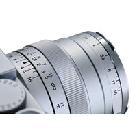 Close-up of a camera lens with focus and aperture scale on a white background