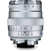 Silver camera lens with focus and aperture scale on a white background