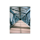 A perspective view down a covered bridge walkway with a blue steel truss structure and a beige floor, framed by repeating blue beams.