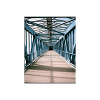 A perspective view down a covered bridge walkway with a blue steel truss structure and a beige floor, framed by repeating blue beams.