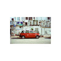 Red and white taxi parked on a city street, captured with the cool blue tones and sharp grain of Amber 400 35mm film.
