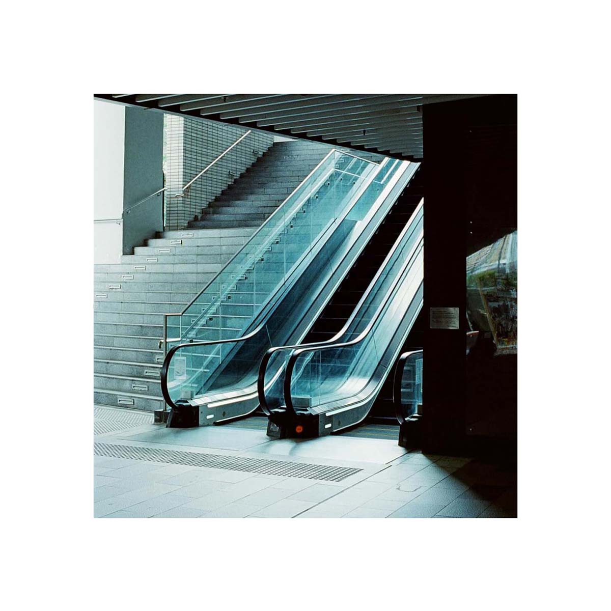 Cinematic shot of a modern escalator and stairs captured on Amber AHU T640 35mm color film with cool, tungsten-balanced tones.