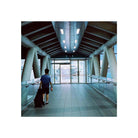 Person walking through a modern, tungsten-lit pedestrian bridge, captured on Amber AHU T640 35mm color film.
