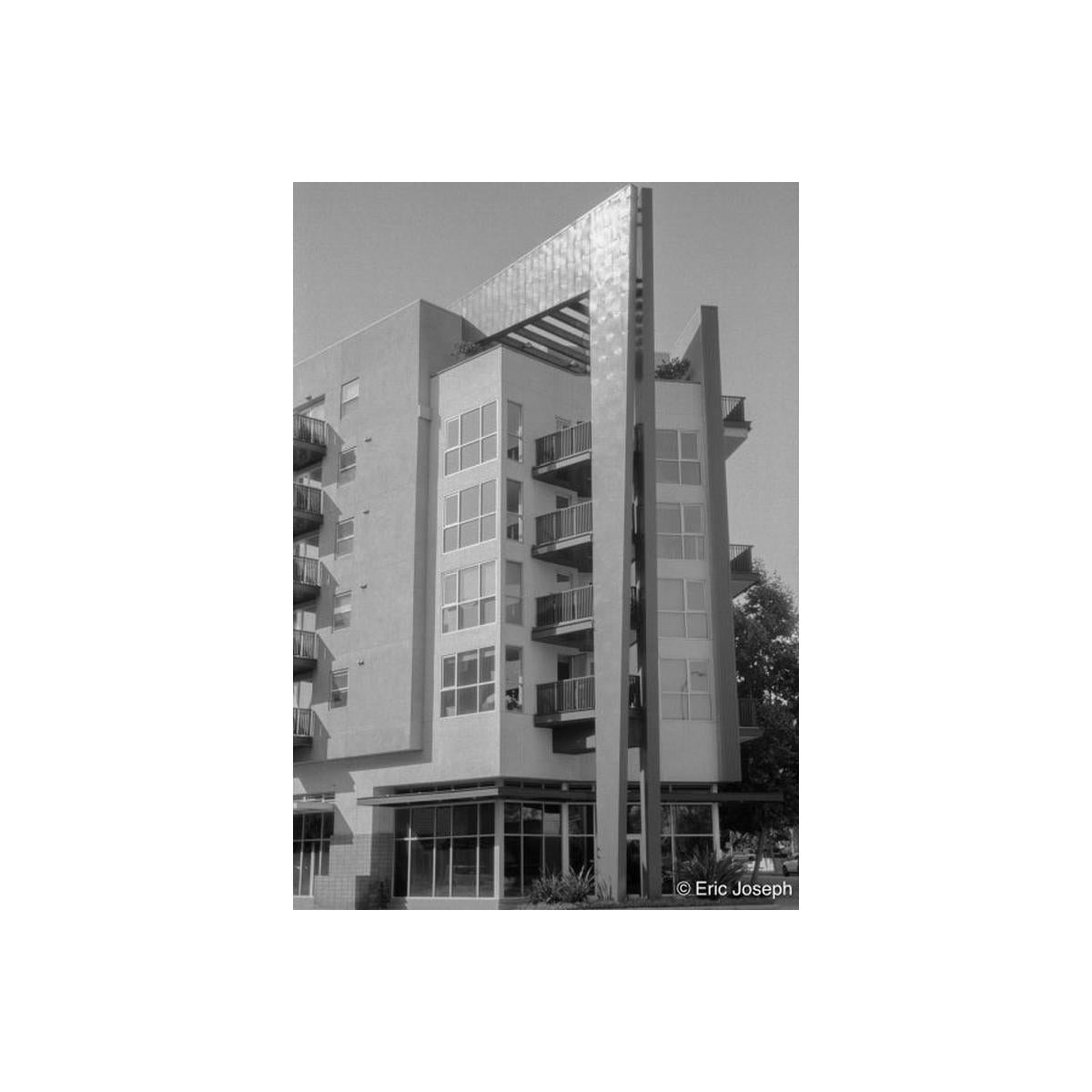 Black and white architectural photograph of a modern apartment building with balconies, shot on Arista EDU 100 film.