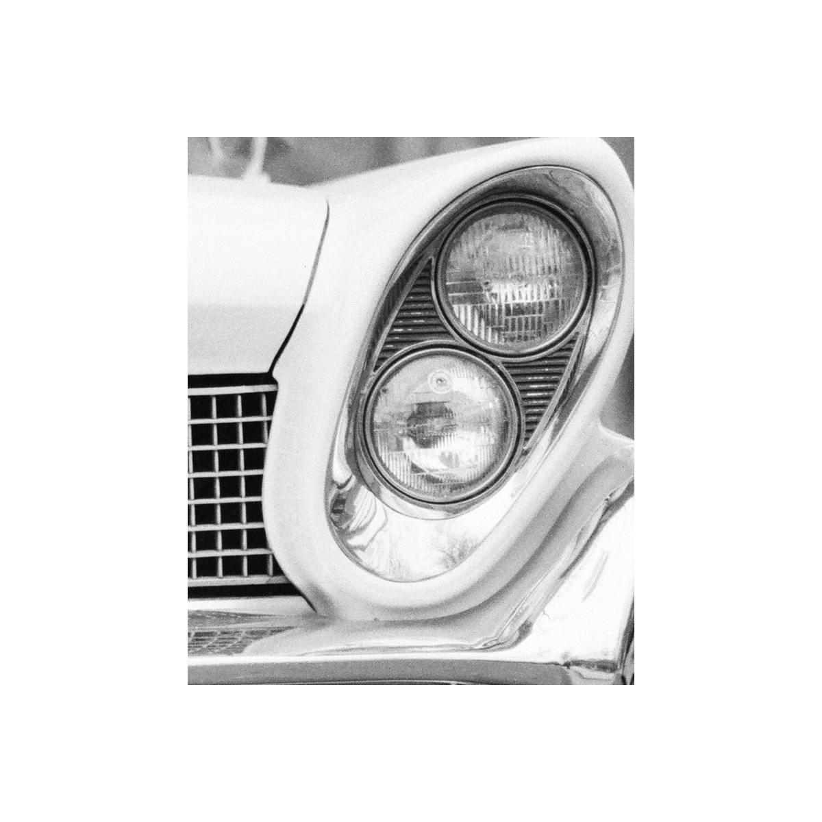 Black and white image of a car angled headlight.