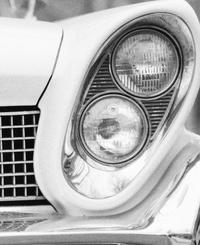 Black and white image of a car angled headlight.
