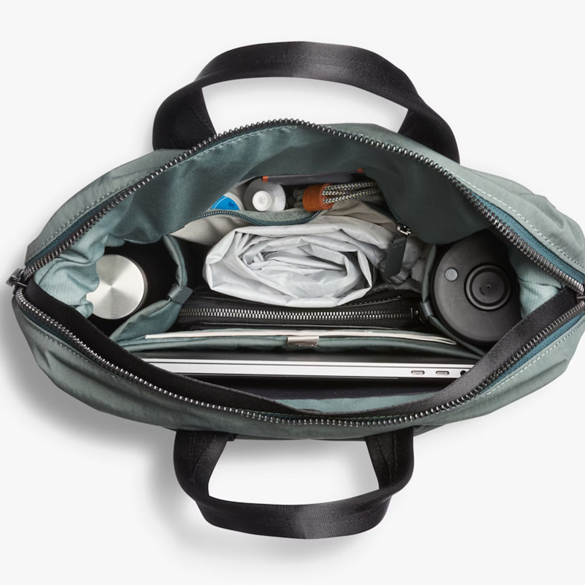 Open Bellroy Totepack bag with laptop, documents, and personal items on a white background
