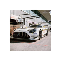 White Mercedes-AMG GT3 race car parked in a pit lane, captured with the vivid colors and fine grain of Candido 200 film.