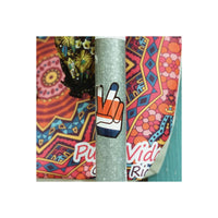 Peace sign sticker on a metal pole against a colorful, patterned fabric background.