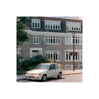 White card parked in front of a light brick building with white windows.