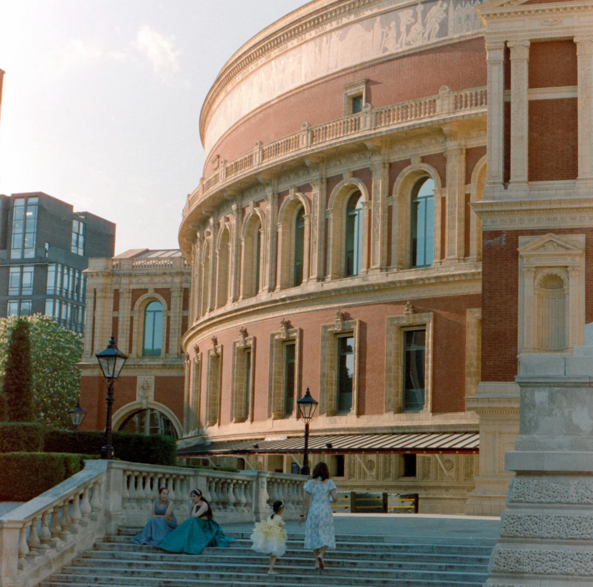 Old circular sand color building with four people on the stairs in front.