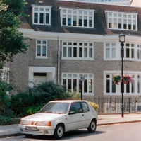White card parked in front of a light brick building with white windows.