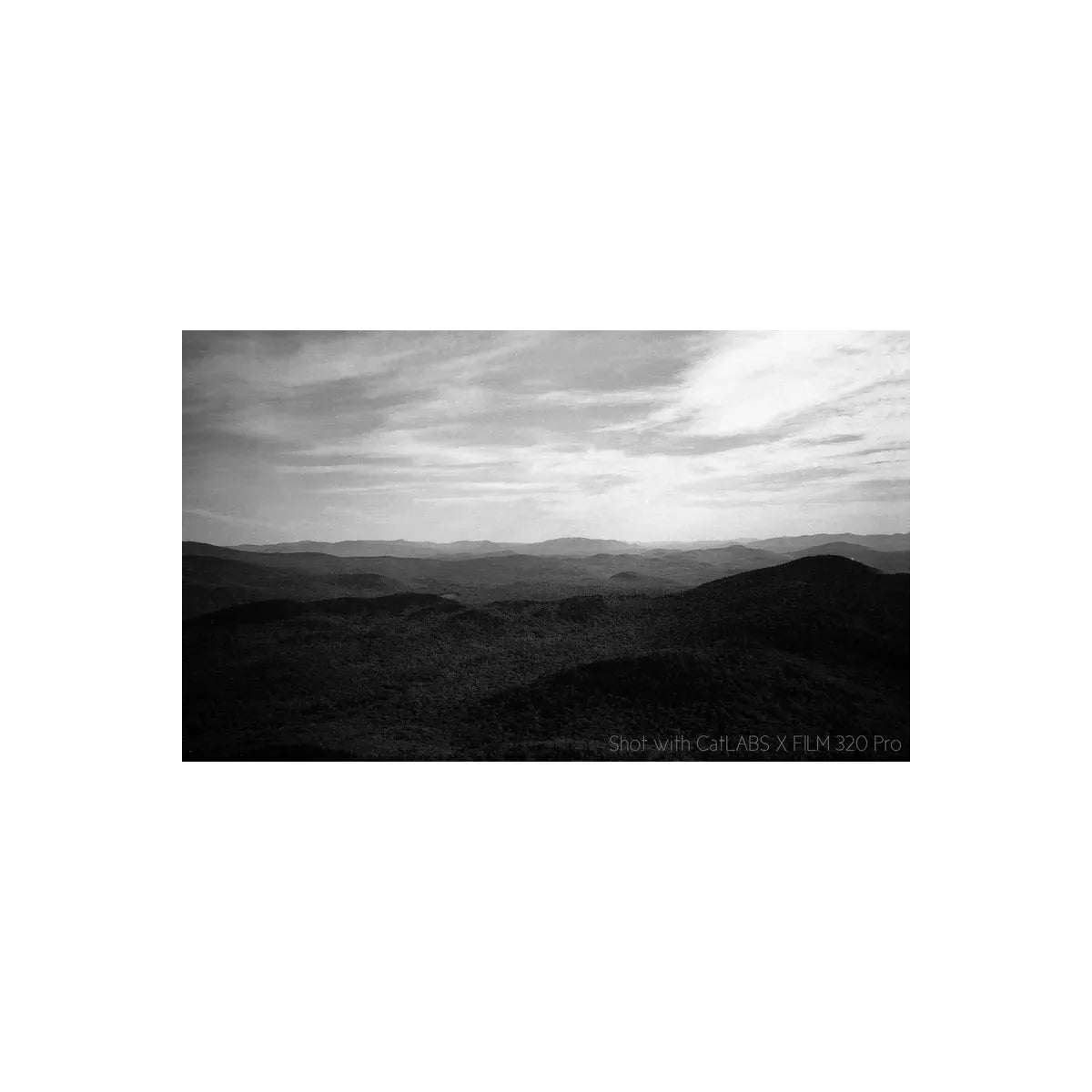 Black and white landscape of rolling hills with a cloudy sky.