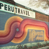 Colorful mural on a building with 'Peru Travel' sign above it