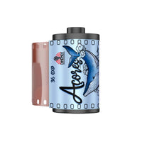 A roll of 36 exp photographic film with a light blue and white design featuring a blue whale illustration and the brand name 'Acores'.