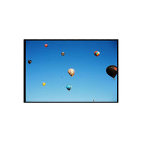 Colorful hot air balloons floating in a clear blue sky, captured on 120 medium format film with a distinct film grain.
