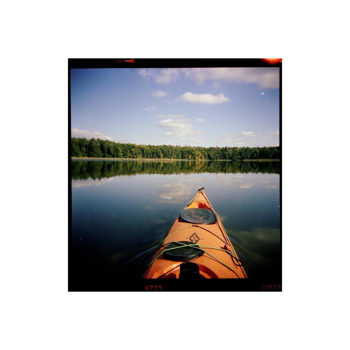 Orange kayak on a calm lake, captured on 120 medium format film with natural colors and a classic film border.