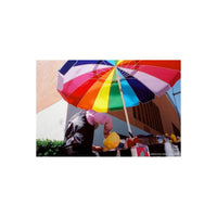 Person under a vibrant rainbow-colored umbrella, captured with CineStill 400Dynamic 35mm film showing warm tones.