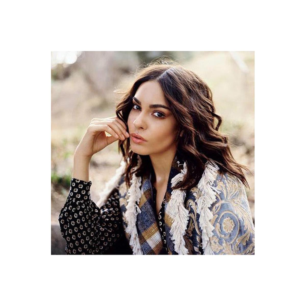 Portrait of a woman with wavy brown hair wearing a patterned shawl, captured with fine grain and warm daylight tones.
