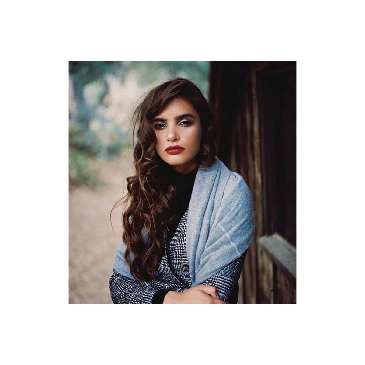 Portrait of a woman with long wavy hair wearing a plaid blazer and blue scarf, shot on CineStill 50Daylight 120 film.