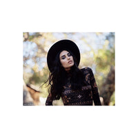Woman in a black hat and patterned top shot on CineStill 50Daylight 120 film with soft, natural bokeh background.