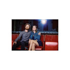 Couple sitting in red vintage theater seats, illuminated by a cinematic light glow, captured on CineStill 800T film.