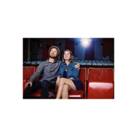 Couple sitting in red vintage theater seats, illuminated by a cinematic light glow, captured on CineStill 800T film.