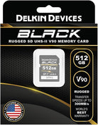Delkin Devices Black 512GB UHS-II SD memory card in its retail packaging, featuring a black and gold design with product specifications and a customer replacement guarantee badge.
