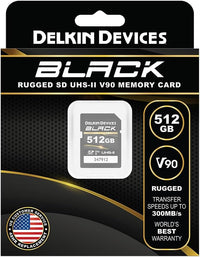 Delkin Devices Black 512GB UHS-II SD memory card in its retail packaging, featuring a black and gold design with product specifications and a customer replacement guarantee badge.