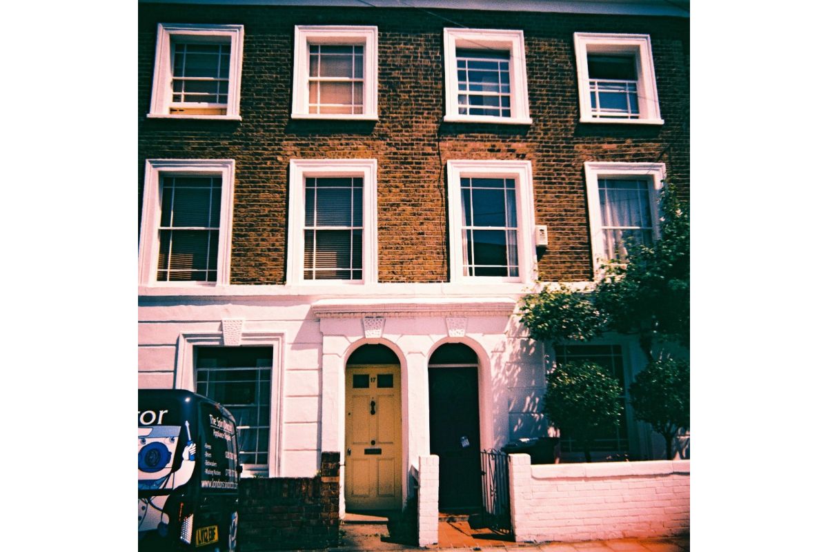 Traditional brick house with white-framed windows and a van parked outside.