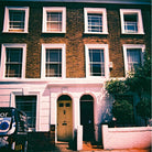 Traditional brick house with white-framed windows and a van parked outside.