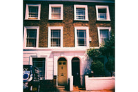 Traditional brick house with white-framed windows and a van parked outside.